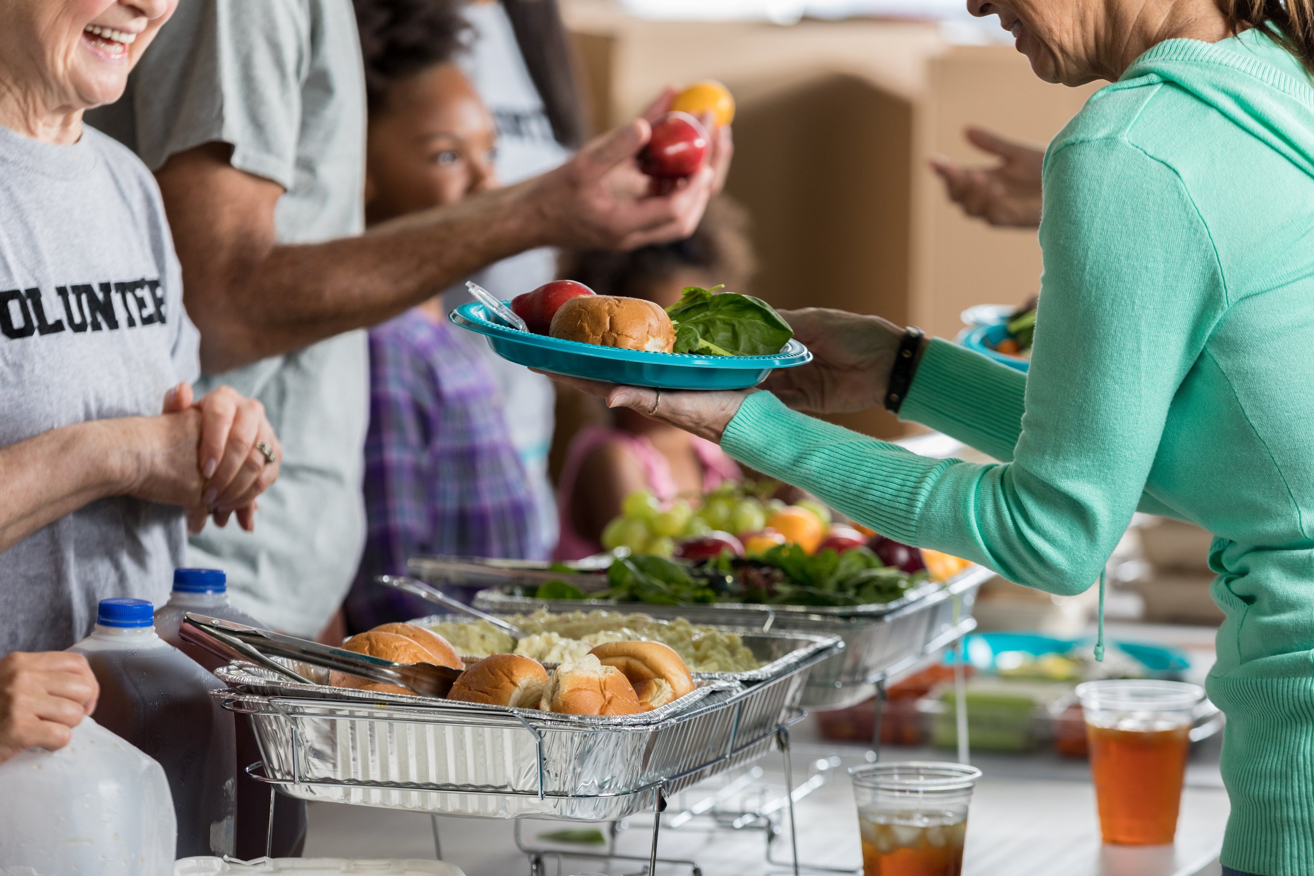 Happy volunteers serve food in homeless shelter