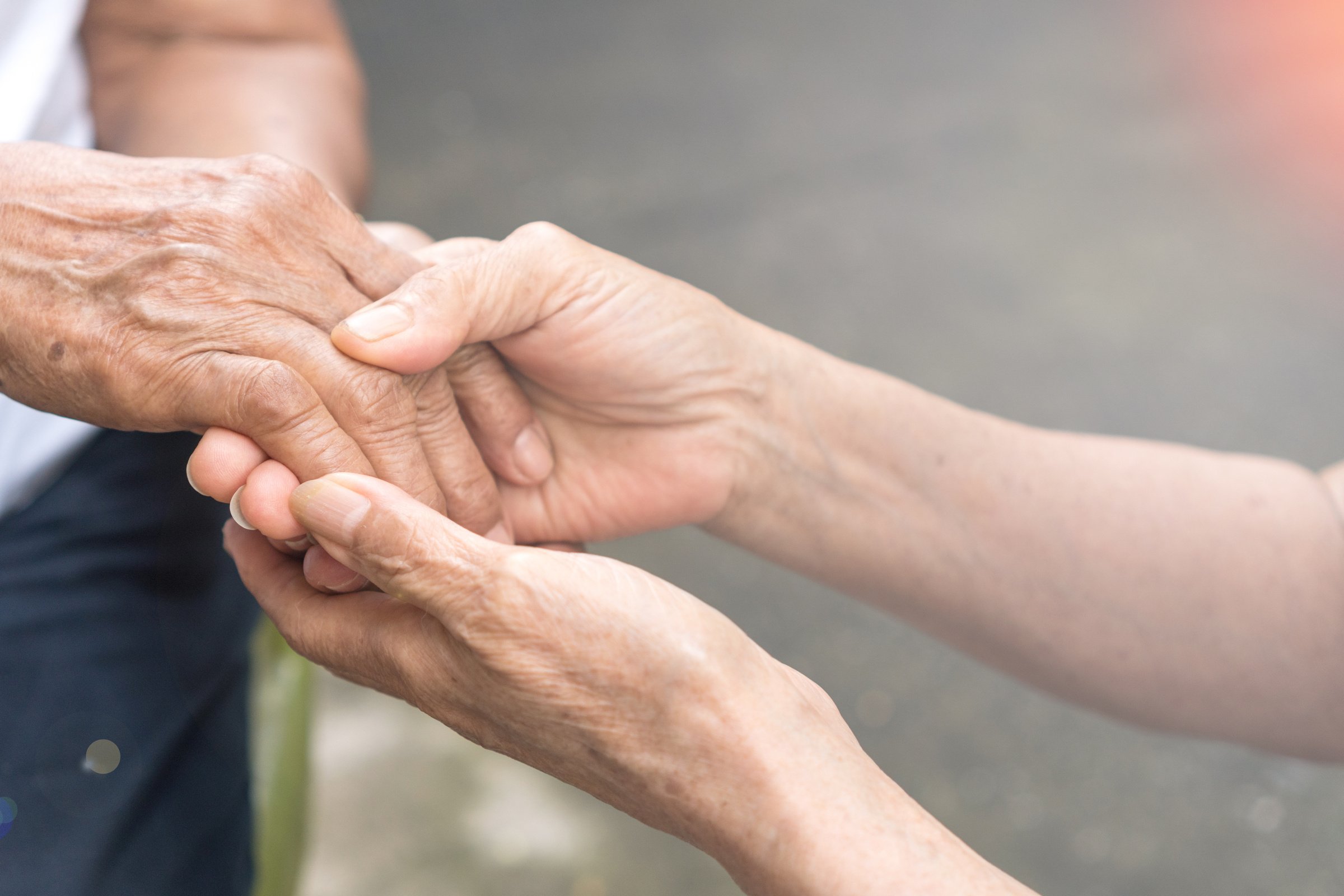 Caregiver, carer hand holding elder hand in hospice care. Philanthropy kindness to disabled concept.